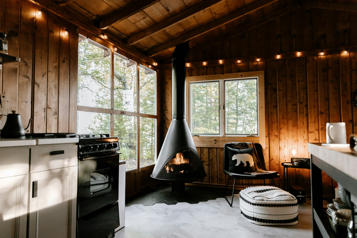 Cabin room with a wood stove and reading chair by the window